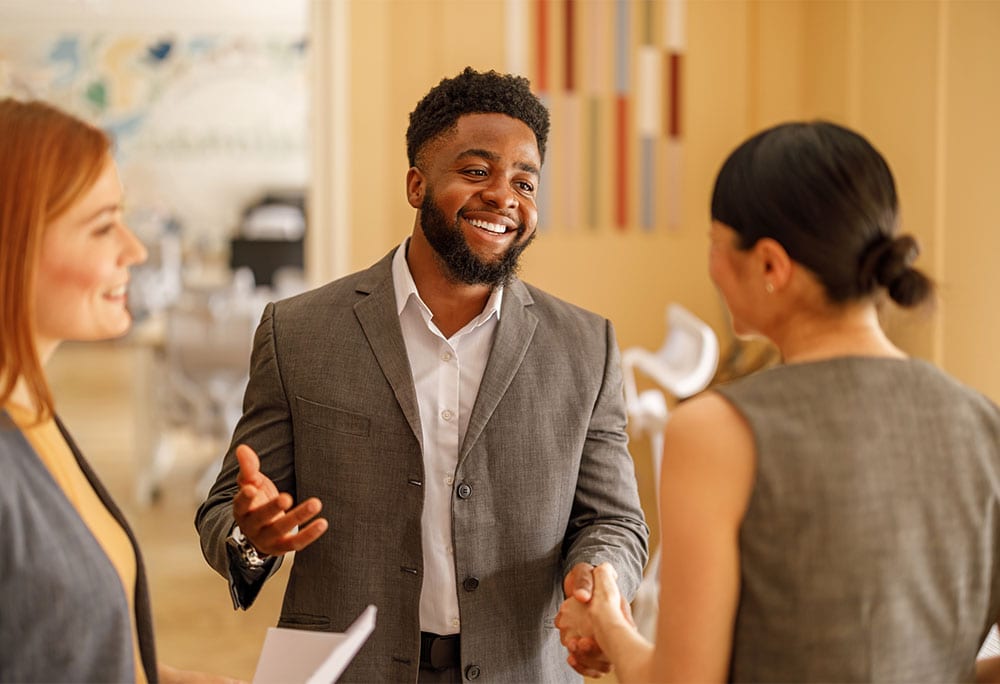 Person in business attire speaking with two other people in an office setting