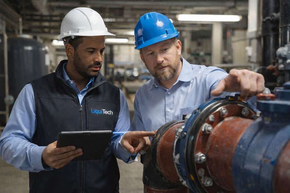 LiquiTech specialist and facility engineer reviewing water management services on a tablet in a mechanical room