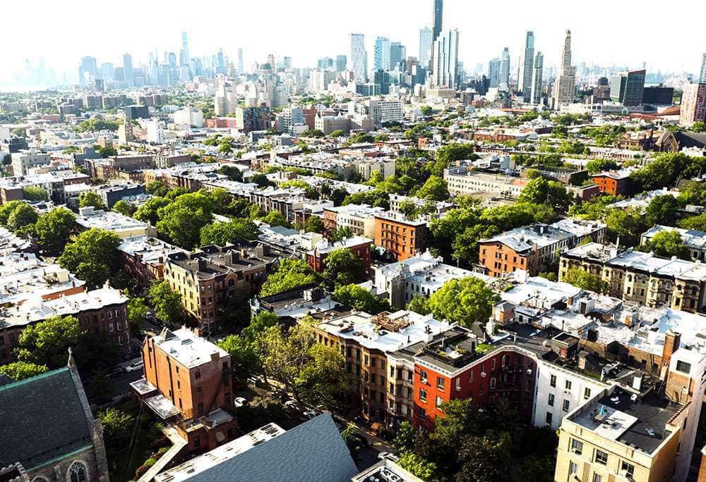 Aerial view of a dense urban residential neighborhood with city skyline on the LiquiTech Multi-Family Residential page