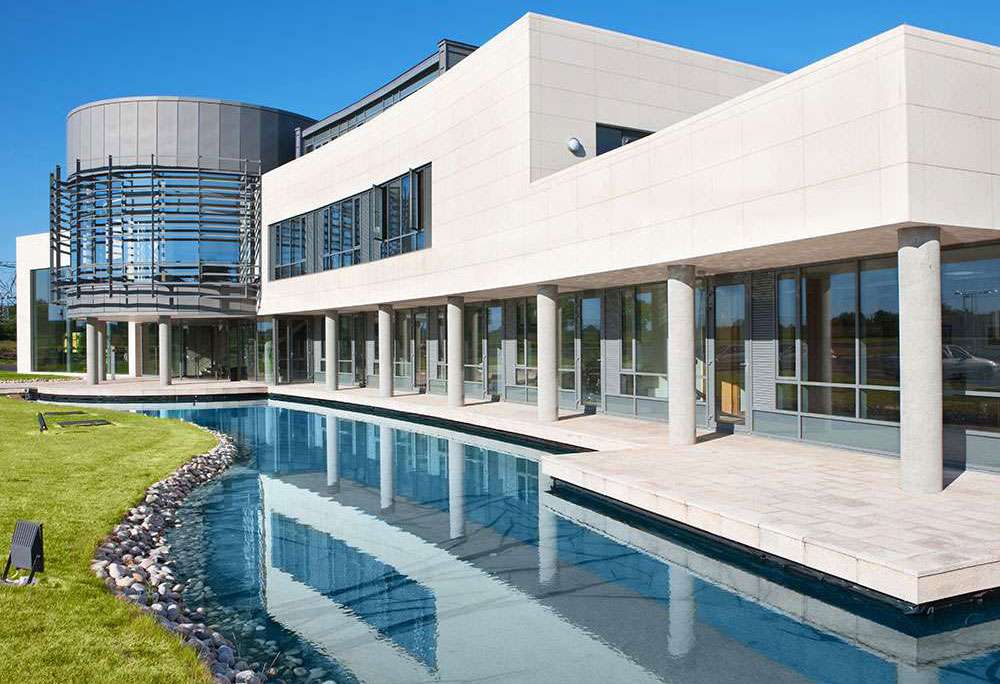 Modern building with a reflective water feature shown beside LiquiTech case study text.