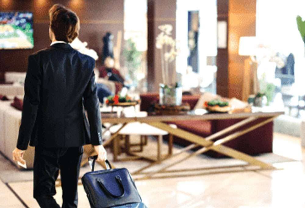 Man with a suitcase walking through a hotel lobby
